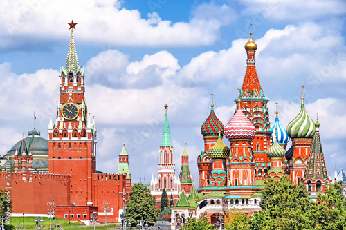 famous moscow city russia kremlin landmark spasskaya clock tower and saint basil's cathedral on red square on summer against blue sky with clouds background. Street view of russian historic heritage