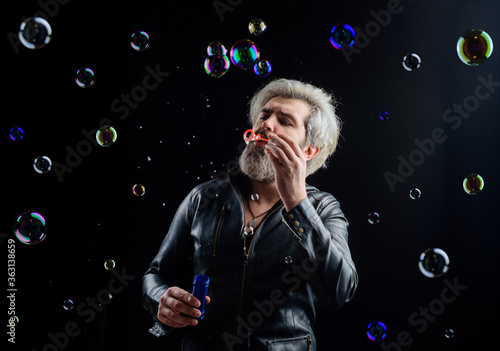 Man blowing bubbles. Soap bubbles. Play with bubbles. Bearded man blowing soap bubbles. Happiness. Child mood. Childhood concept.