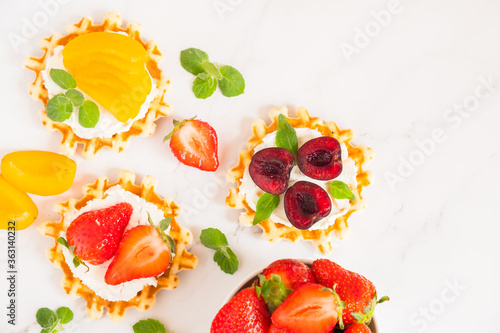 Fototapeta Naklejka Na Ścianę i Meble -  Top view of traditional Belgian waffles with soft cheese, fruits and berries with copy space. flat lay.