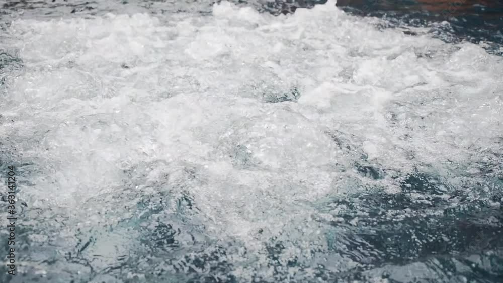 Close up fizzing, erupting clear water in empty blue swimming pool, SPA hydrotherapy concept. Top view of stream bubbles, splashes in a jacuzzi. Close up fizzing, erupting clear water in empty blue swimming pool, SPA hydrotherapy concept. Top view of stream bubbles, splashes in a jacuzzi.