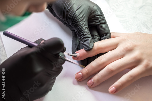  The process of creating a manicure. Closeup shot of a woman in a salon. Beautician puts nails on a client.