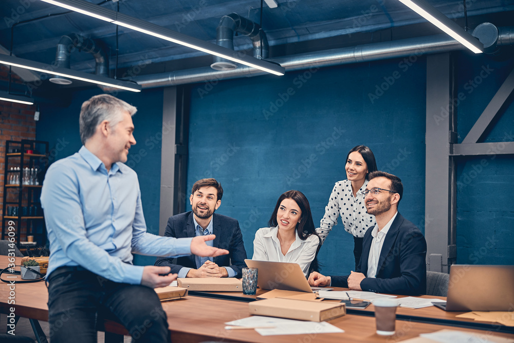 Employees sitting and holding a meeting at a large table Employees sitting and holding a meeting at a large table
