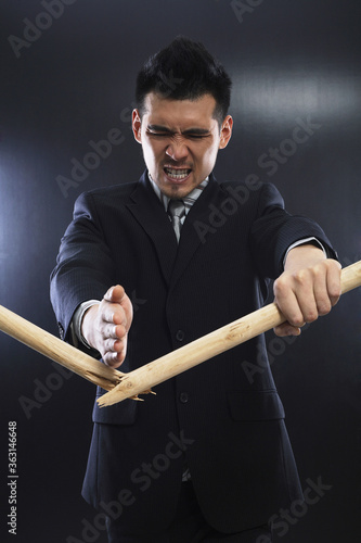 Businessman chopping stick with his bare hand photo