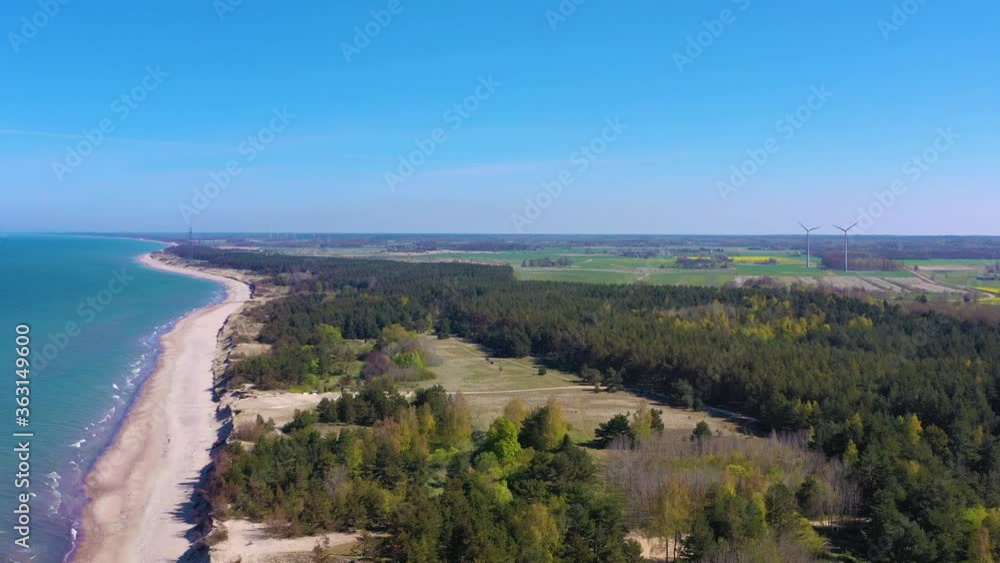 Aerial view flying over pine forest towards wind turbines. Sea sand beach Aerial view flying over pine forest towards wind turbines. Sea sand beach