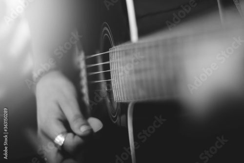 Closeup of a man playing the guitar strings in monochrome