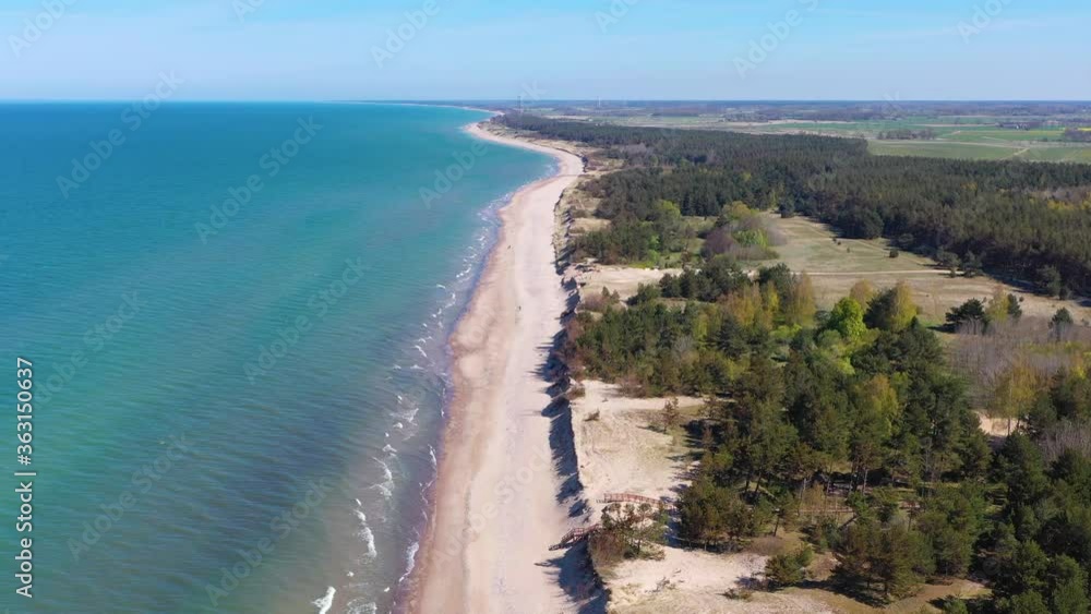 Aerial view flying along Latvian Baltic sea seaside beach coast towards wind turbine near Liepaja Aerial view flying along Latvian Baltic sea seaside beach coast towards wind turbine near Liepaja