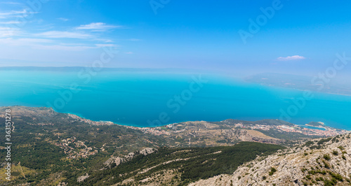 Panoramic view of the Adriatic sea from the skywalk on biokovo mountain. View of Makarska, Tucepi and Podgora coastal cities. Combination of rural hills and trees descending into the sea © Antonio