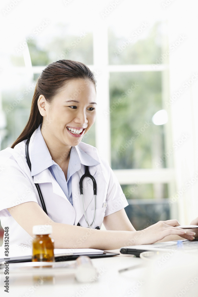 Female doctor smiling while using laptop Female doctor smiling while using laptop