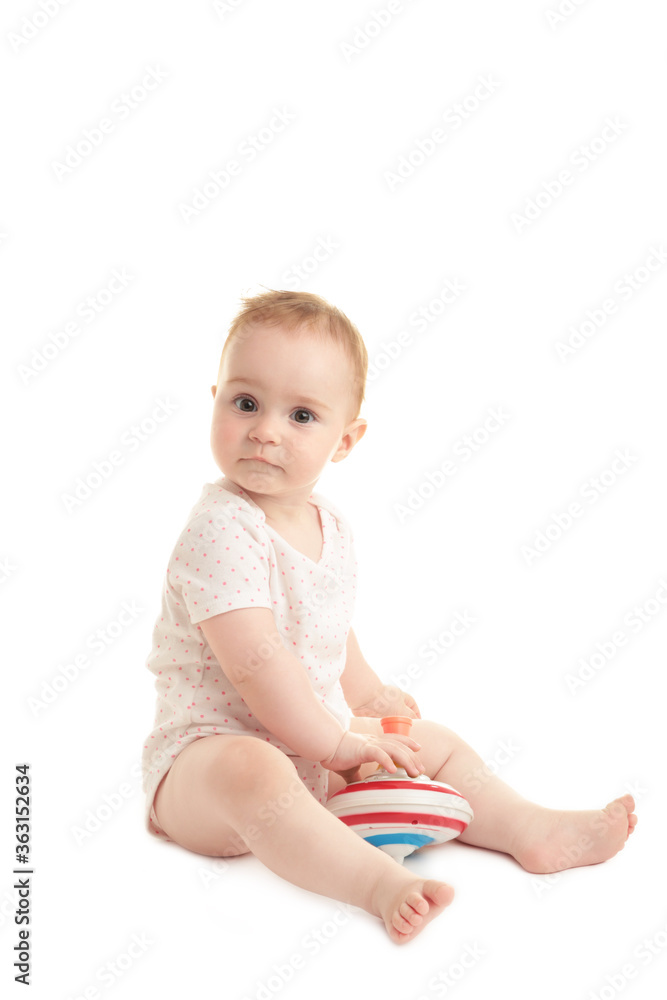 Cute baby girl sitting and playing with a toy isolated on white background Cute baby girl sitting and playing with a toy isolated on white background