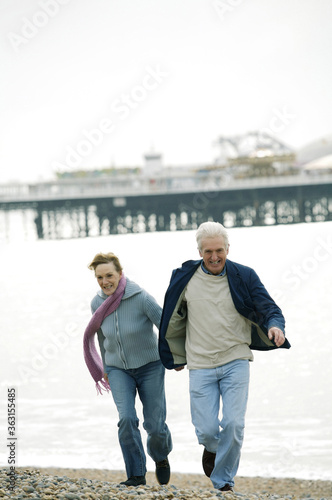 A couple holding hands and running on the beach happily