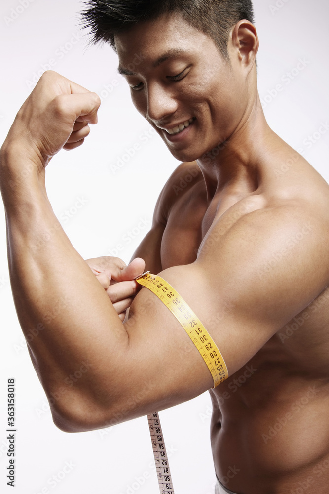 Man measuring his muscular arm