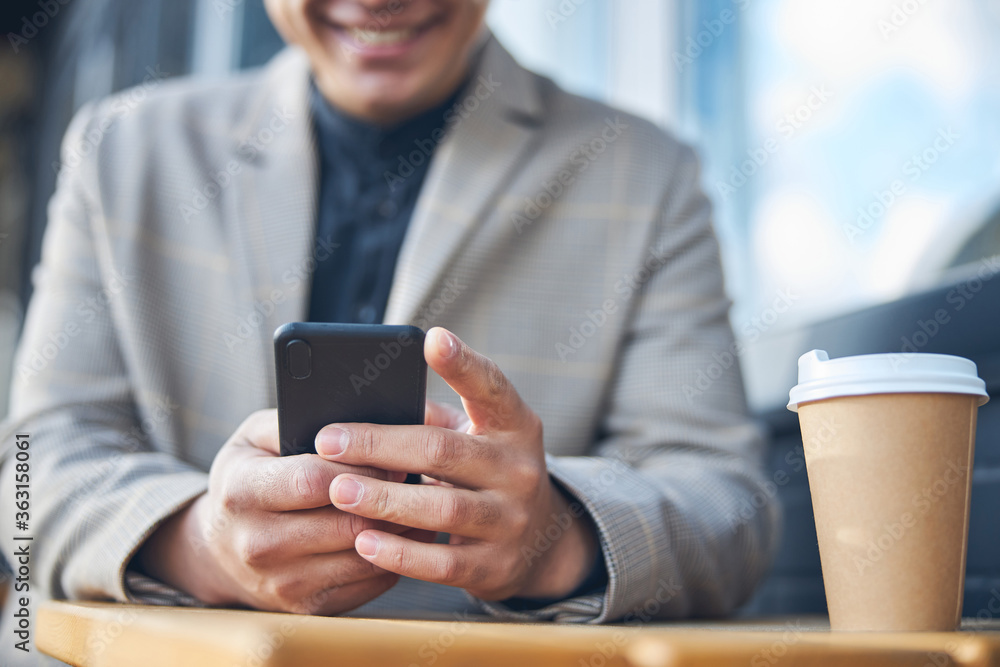 Smiling young man using modern smartphone in outdoor cafe Smiling young man using modern smartphone in outdoor cafe