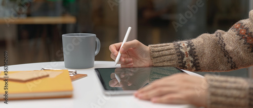 Female worker working from home with mock-up tablet and stationery on coffee table