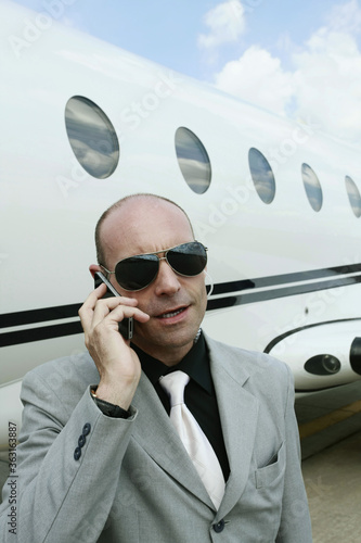 Man talking on the phone with private jet in the background