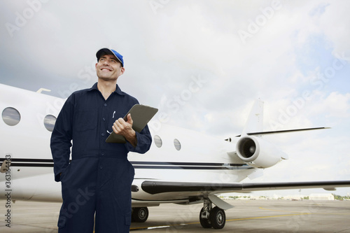 Mechanic holding clipboard with private jet in the background