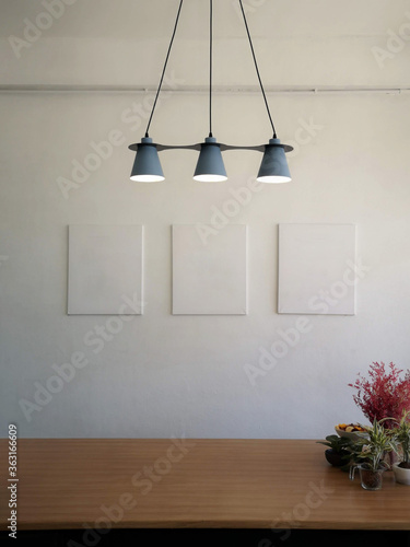 The gray lamp and the white wall have blank picture frames photo