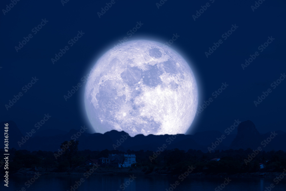 Full Snow Moon on night sky back silhouette mountain hill over lake Full Snow Moon on night sky back silhouette mountain hill over lake