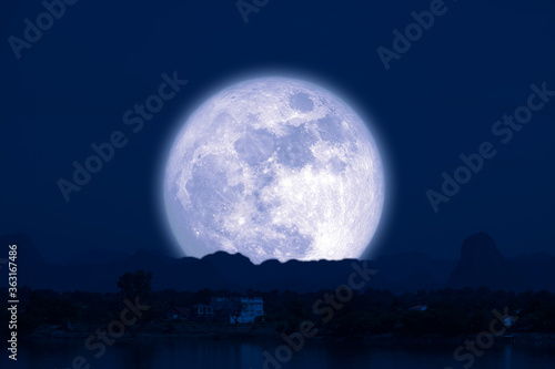 Full Snow Moon on night sky back silhouette mountain hill over lake