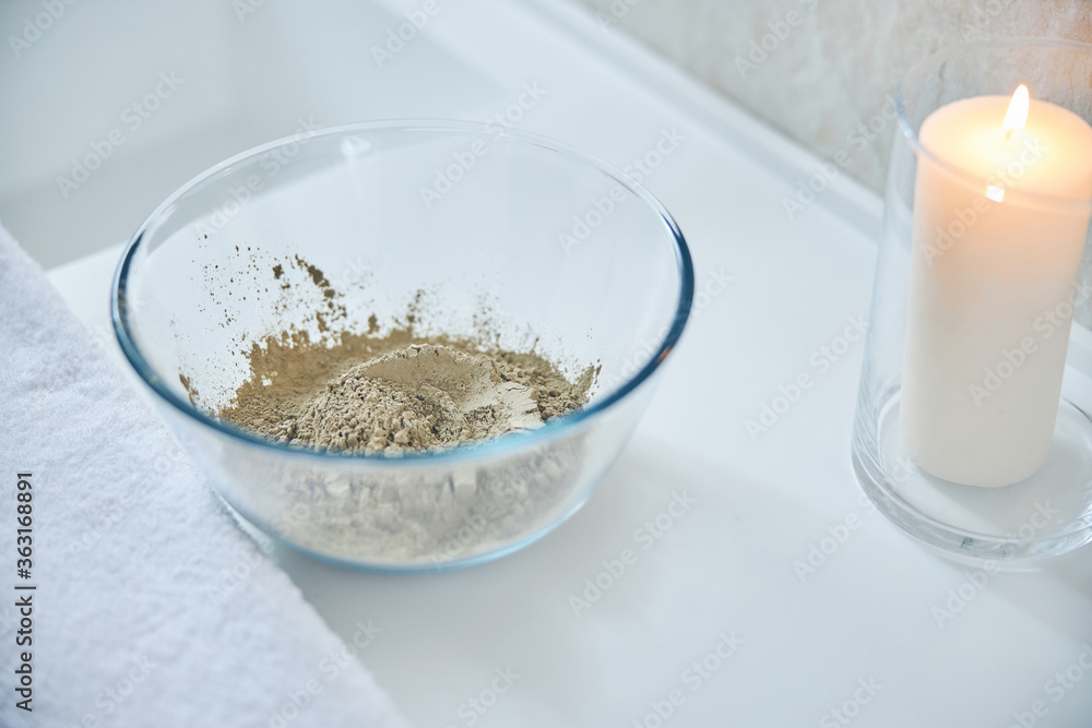 Dry clay powder in glass bowl on white surface Dry clay powder in glass bowl on white surface