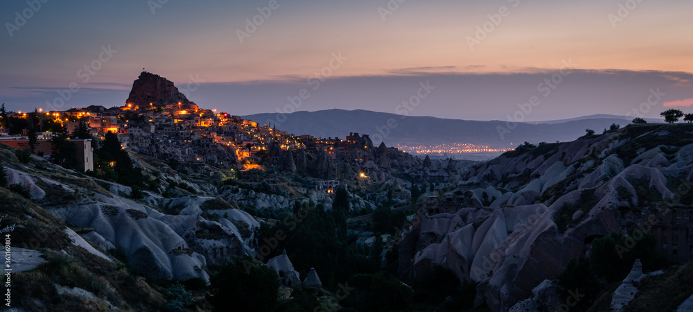 Panoramic landscape of Uchisar castle at night in Cappadocia, Central Anatolia, Turkey. Panoramic banner portion