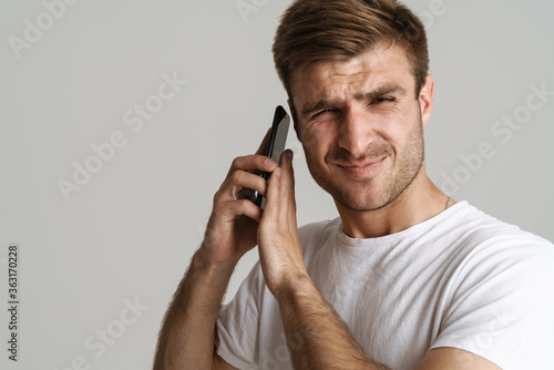 Portrait of handsome displeased man talking on mobile phone