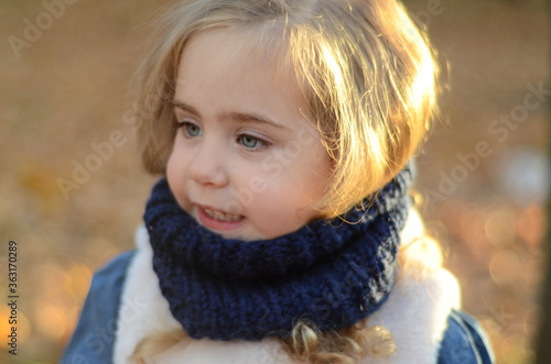 Picture of a smiling blonde toddler girl playing outside wearing the knitted snood