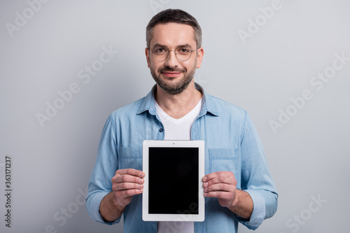 Close-up portrait of his he nice attractive cheerful content gray-haired guy seller holding in hands new tablet demonstrating isolated over gray light pastel color background