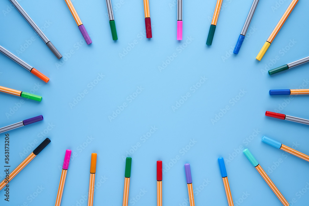 Naklejka premium Colored markers making a circle with copy space in the center on a blue background. Back to school, design, creativity concept and crafts.