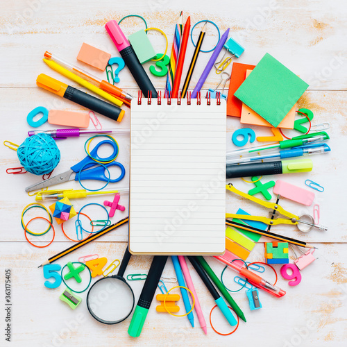 Notebook with school objects in wooden background.