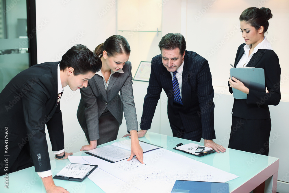 Business people reviewing blueprints together Business people reviewing blueprints together