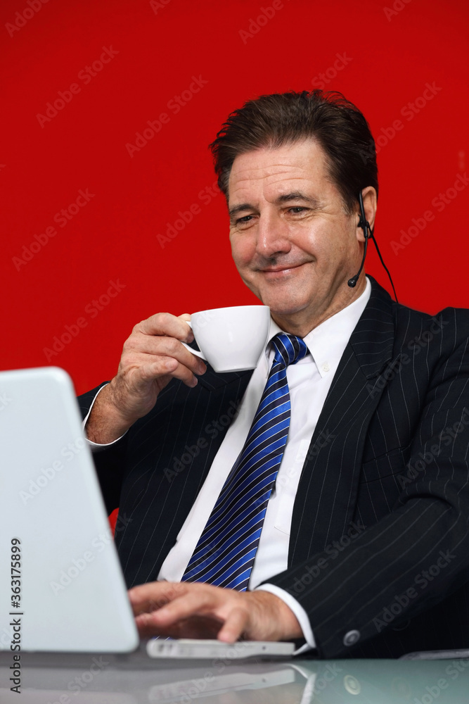 Businessman drinking coffee while video conferencing on laptop Businessman drinking coffee while video conferencing on laptop