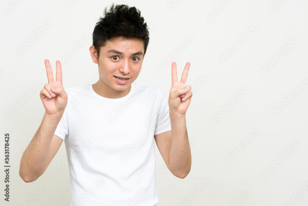 Portrait of happy young handsome Asian man with braces showing peace sign