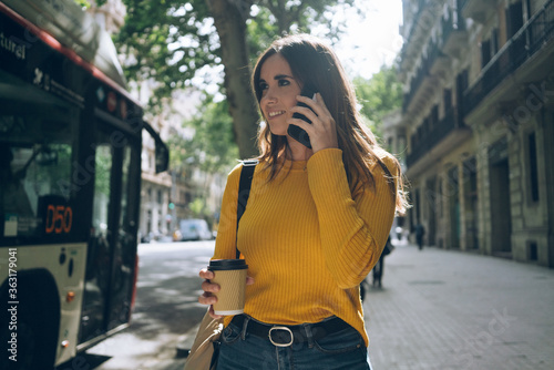 Lifestyle portrait of happy attractive casual woman walking in the city on a sunny day, beautiful young girl dressed in casual style  girl dressed in casual style talking on smartphone photo