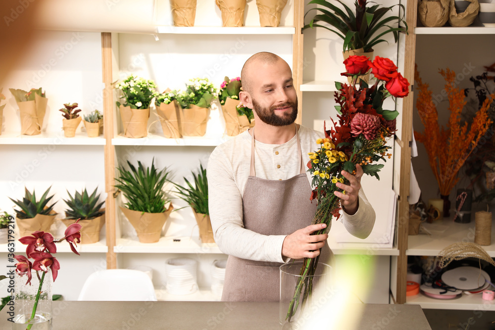 Florist making bouquet with fresh flowers at table in shop Florist making bouquet with fresh flowers at table in shop