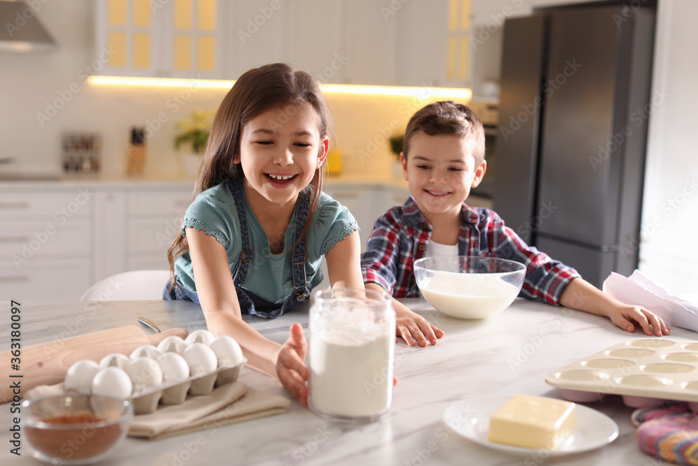 Cute little children cooking dough in kitchen at home Cute little children cooking dough in kitchen at home
