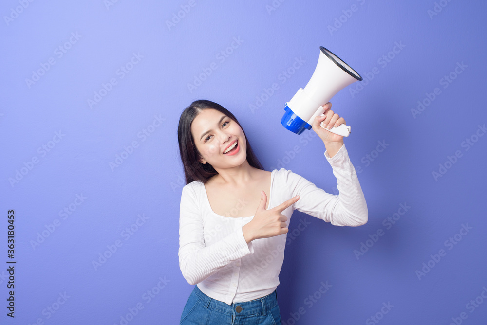 portrait of young beautiful smiling woman is using megaphone to announce over isolated purple background studio portrait of young beautiful smiling woman is using megaphone to announce over isolated purple background studio