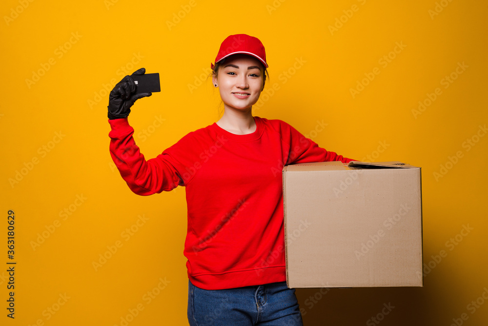 Young asian delivery woman holding box and blank on yellow background Young asian delivery woman holding box and blank on yellow background