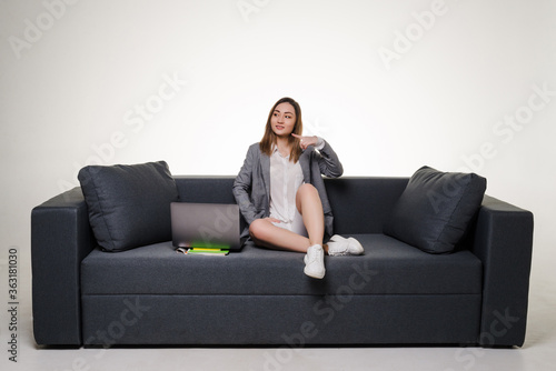Beautiful asian woman on a sofa working with a laptop pointed side in white background © dianagrytsku