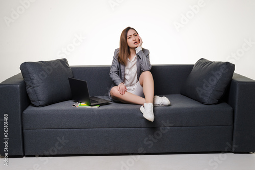 Young woman on tired sitting on her white sofa with laptop isolated on white background