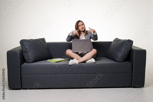 Young asian woman pointed on laptop sitting on sofa isolated on white background photo