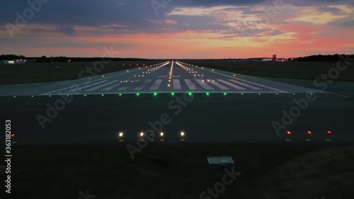 Aerial view on empty airport runaway with markings for landings and all navigation lights (ILS Cat II) on at the colorful sunset, clear for airplane landing or taking off in Wroclaw airport photo