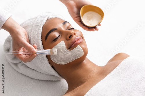 Top view of beauty therapist applying face mask photo