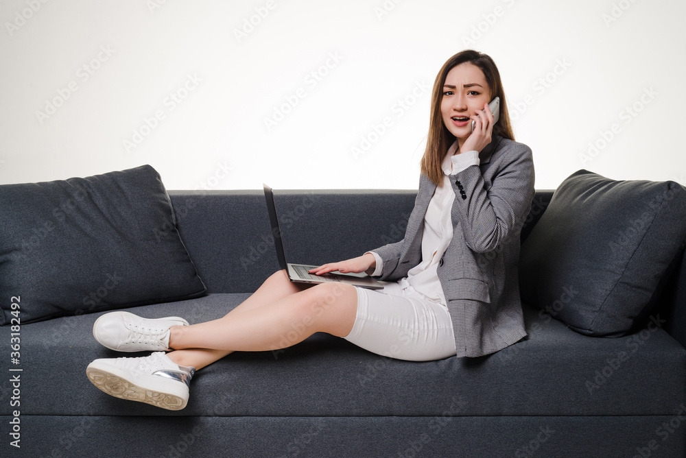 Asian woman on the phone using laptop at home in the living room. Asian woman on the phone using laptop at home in the living room.