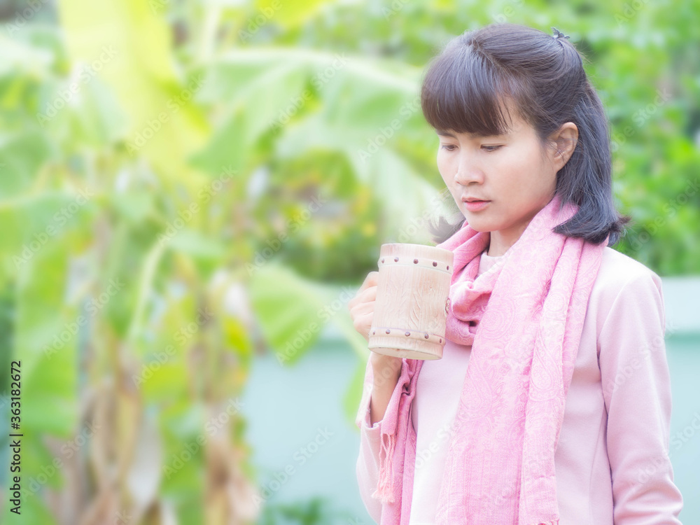 Woman holding a brown coffee cup with hot coffee on blur image of green background. lady drinking coffee in a morning. Woman holding a brown coffee cup with hot coffee on blur image of green background. lady drinking coffee in a morning.