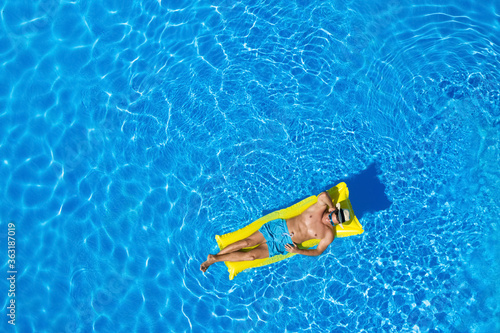 Young man with inflatable mattress in swimming pool, top view. Space for text