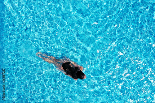 Beautiful young woman swimming in pool, top view. Space for text © New Africa