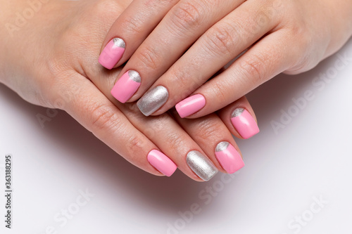 Light pink manicure with silver sparkles on square short nails closeup on a white background. Pink-silver manicure.