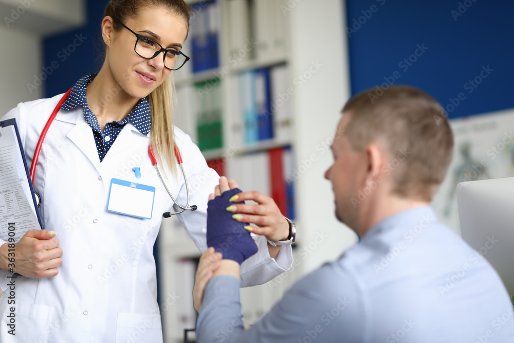 Obraz premium Young female doctor is helping patient. Elastic bandage fixation concept