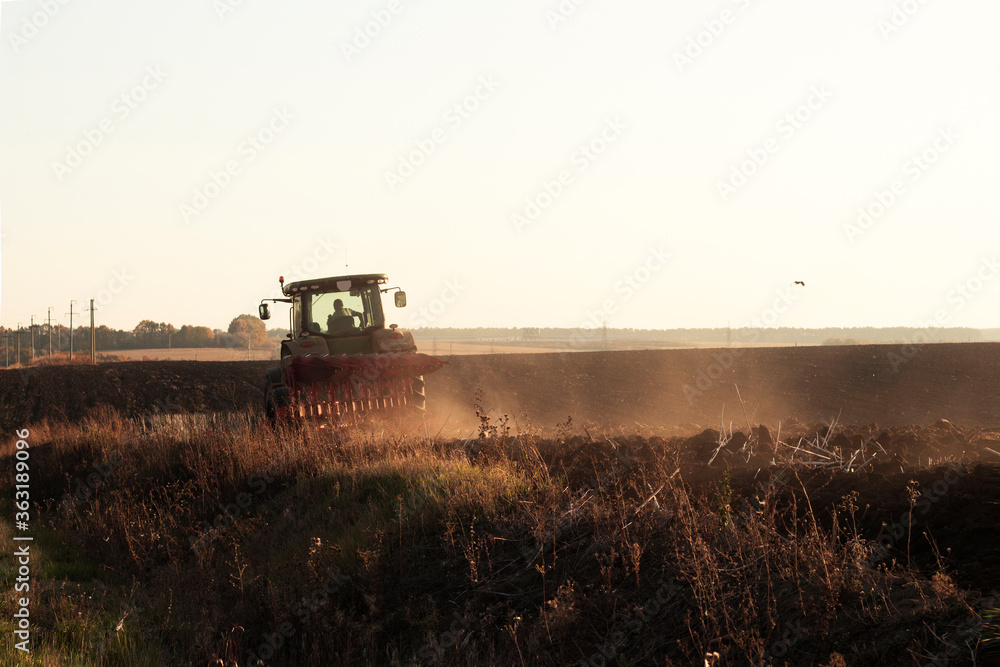Farmer in tractor plowing the field in the beautiful evening sunset