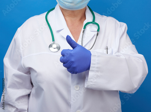 woman in white coat, wearing blue medical latex gloves on her hands,showing like gesture with his  hand